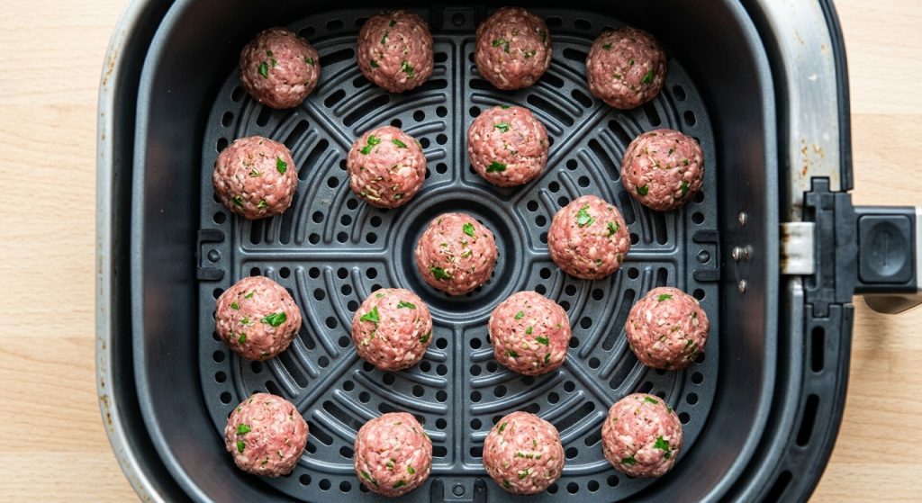 Greek meatballs arranged in a single layer in an air fryer basket